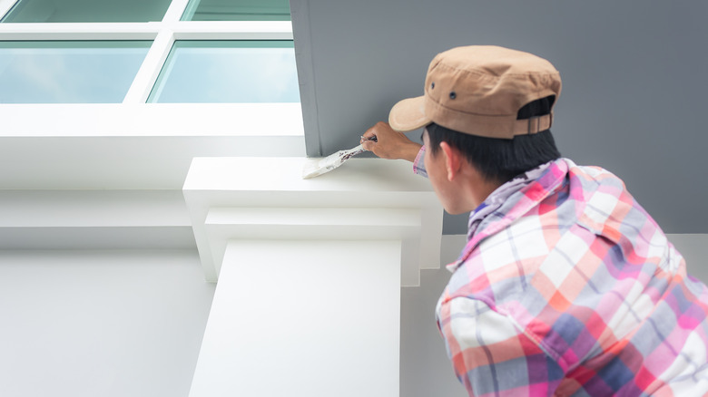 person painting trim on porch